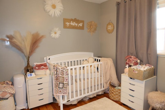 bedroom featuring a nursery area and wood finished floors