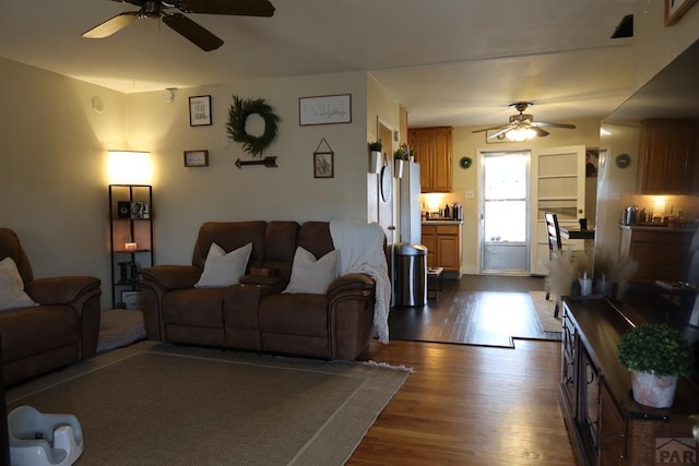 living room with ceiling fan and dark wood-type flooring