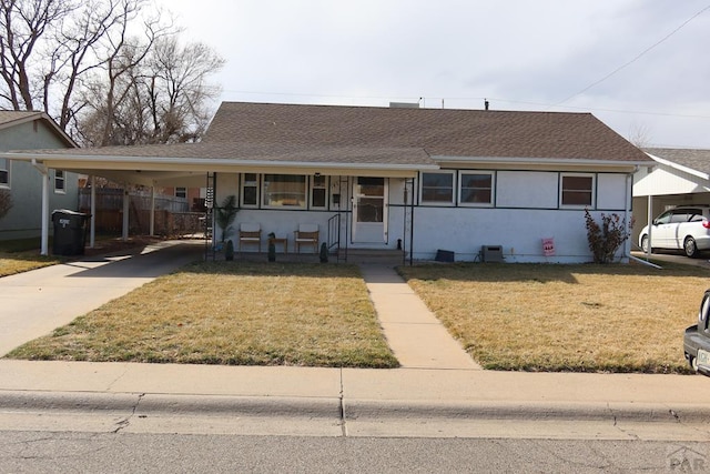 view of front of house featuring stucco siding, a shingled roof, concrete driveway, a carport, and a front lawn