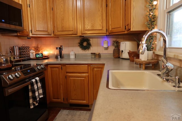 kitchen featuring appliances with stainless steel finishes, backsplash, a sink, and light countertops