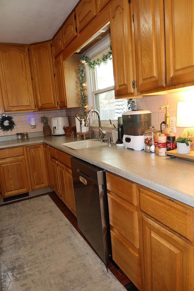 kitchen with decorative backsplash, dishwasher, brown cabinets, light countertops, and a sink