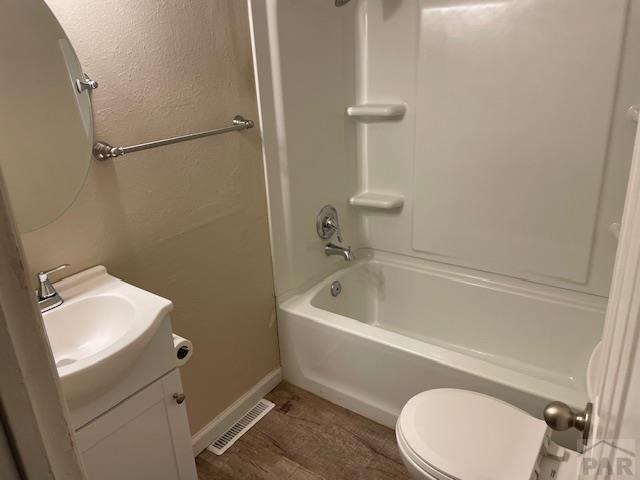 bathroom featuring visible vents, a textured wall, toilet, tub / shower combination, and vanity