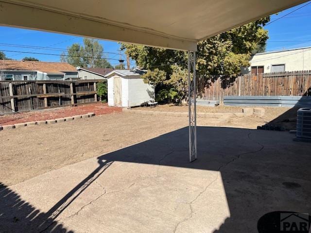 view of yard featuring an outbuilding, a patio area, fence, and a storage shed