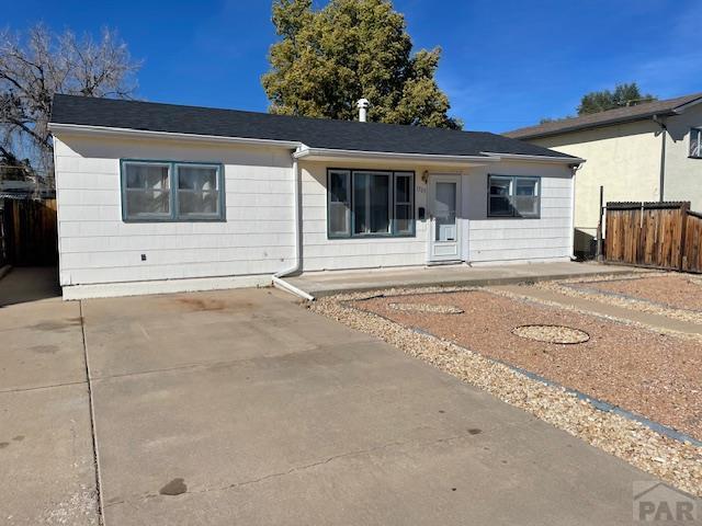 ranch-style home featuring driveway and fence