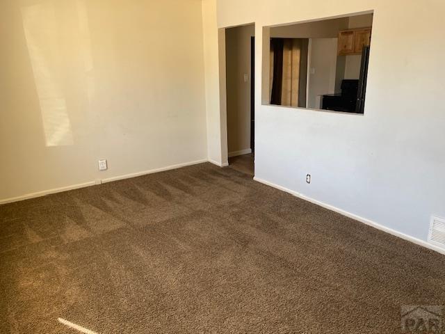 spare room with dark carpet and baseboards