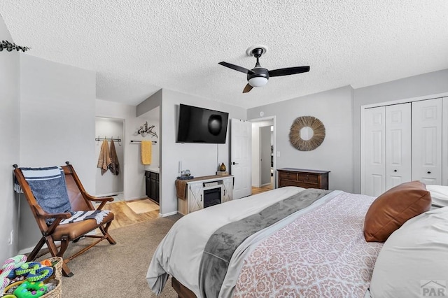 bedroom with a ceiling fan, a textured ceiling, connected bathroom, a closet, and a fireplace