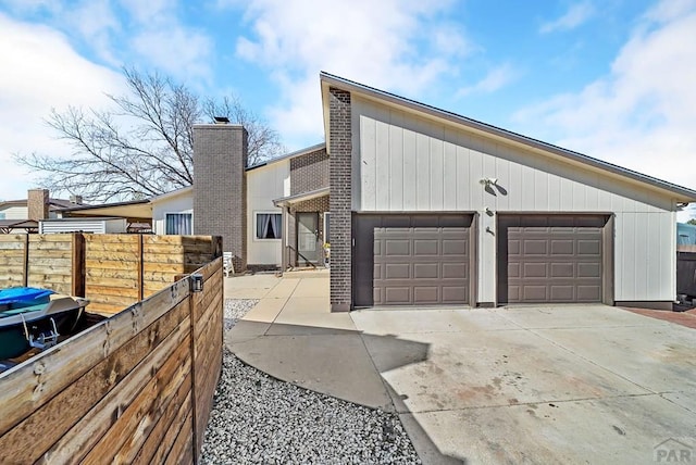 view of front of house featuring brick siding, driveway, and fence