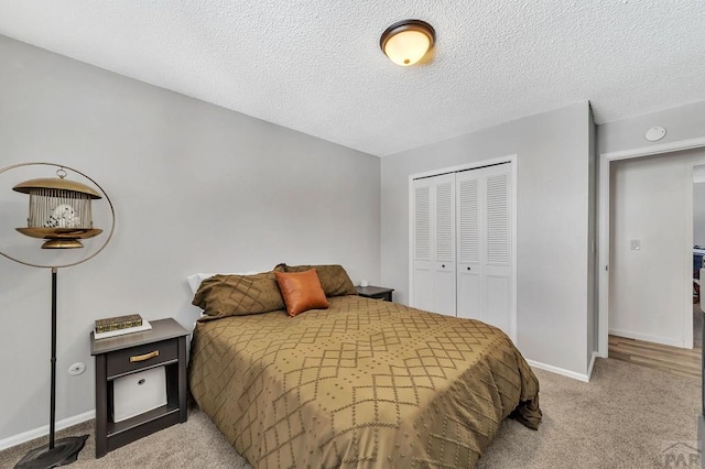 bedroom with a closet, a textured ceiling, baseboards, and carpet floors