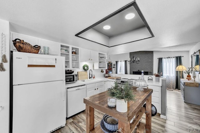 kitchen with a sink, open shelves, white appliances, a peninsula, and light countertops