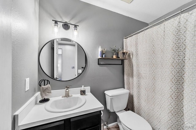 bathroom with a shower with shower curtain, toilet, vanity, and a textured wall