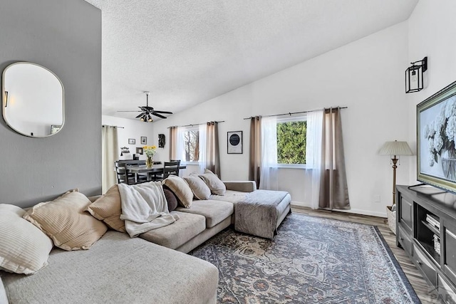 living room featuring baseboards, ceiling fan, vaulted ceiling, wood finished floors, and a textured ceiling