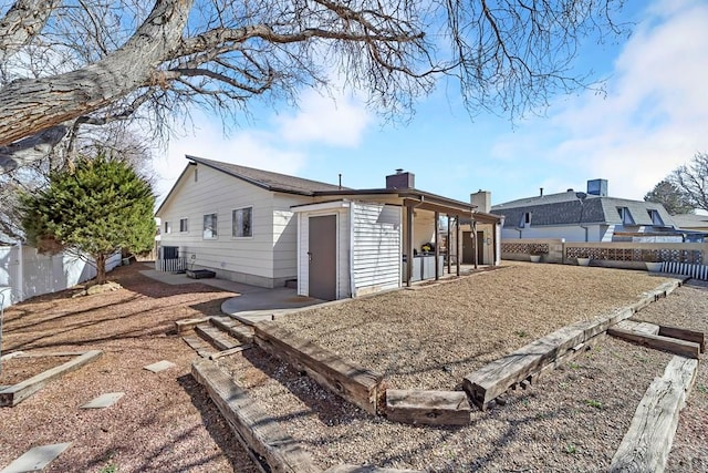 view of side of property featuring a fenced backyard, a chimney, and a patio area