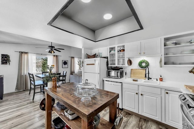 kitchen with open shelves, stainless steel appliances, white cabinetry, a raised ceiling, and a sink