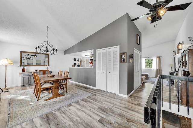 dining area featuring ceiling fan with notable chandelier, a textured ceiling, baseboards, and wood finished floors