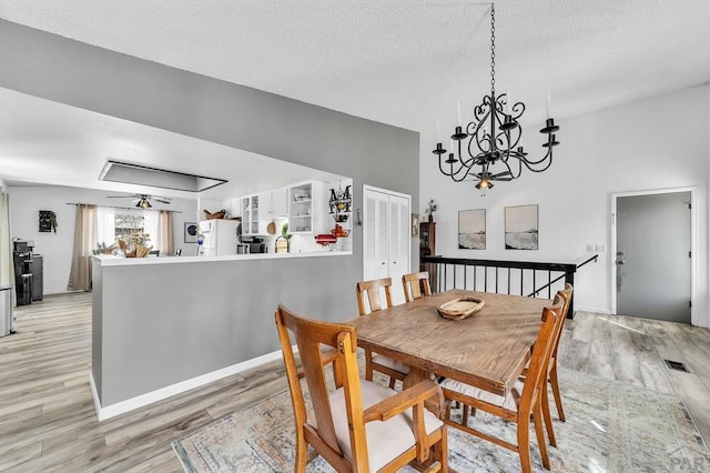 dining area featuring visible vents, ceiling fan with notable chandelier, light wood-style floors, and a textured ceiling