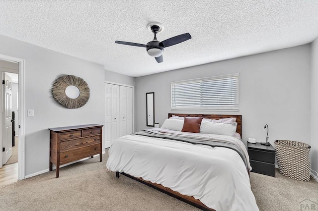 bedroom featuring baseboards, carpet, a closet, a textured ceiling, and a ceiling fan