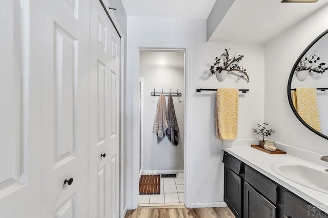 bathroom with baseboards, a textured ceiling, wood finished floors, and vanity