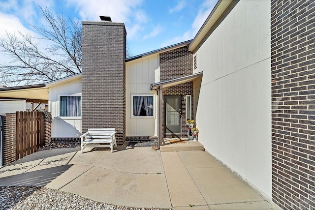 exterior space with brick siding, a chimney, a patio, and fence