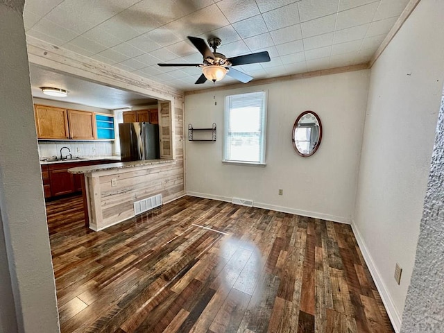 kitchen with light countertops, visible vents, brown cabinetry, freestanding refrigerator, and dark wood-type flooring