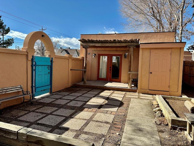 view of outbuilding featuring a gate, fence, and french doors