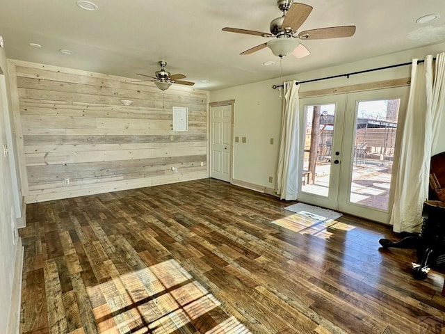 unfurnished living room featuring dark wood-type flooring, recessed lighting, french doors, and wooden walls