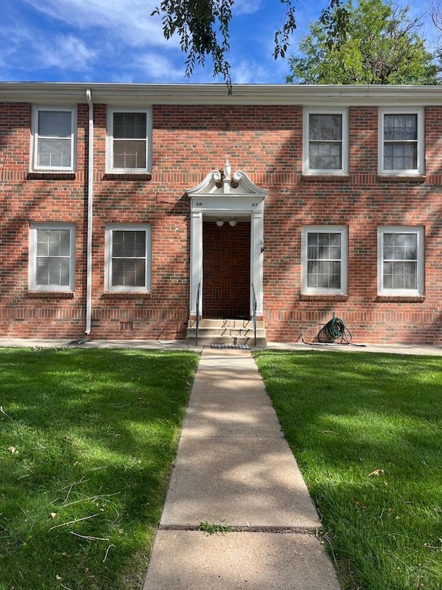 view of front of home featuring a front yard, brick siding, and entry steps