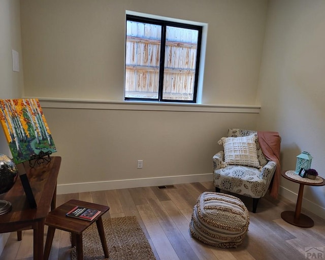 sitting room with visible vents, baseboards, and wood finished floors