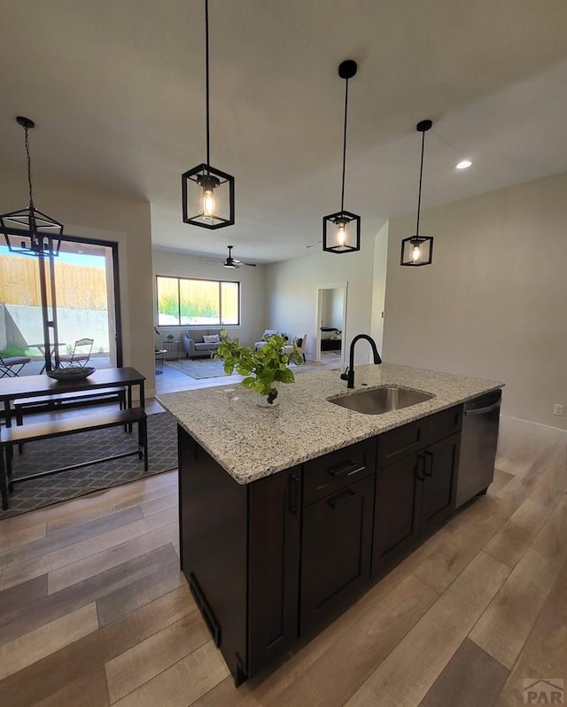 kitchen featuring open floor plan, a sink, hanging light fixtures, and a center island with sink