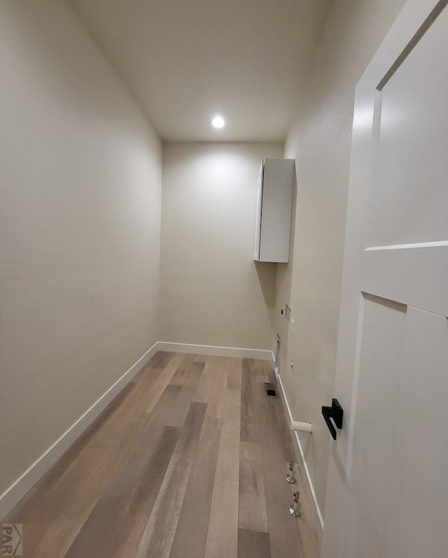 laundry area featuring laundry area, baseboards, and wood finished floors