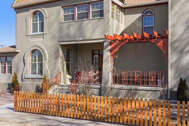 view of front facade with a shingled roof, a fenced front yard, and stucco siding