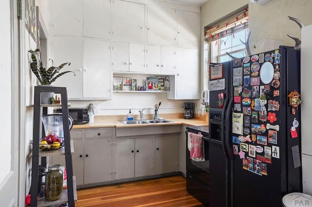 kitchen featuring a sink, black appliances, open shelves, and light countertops