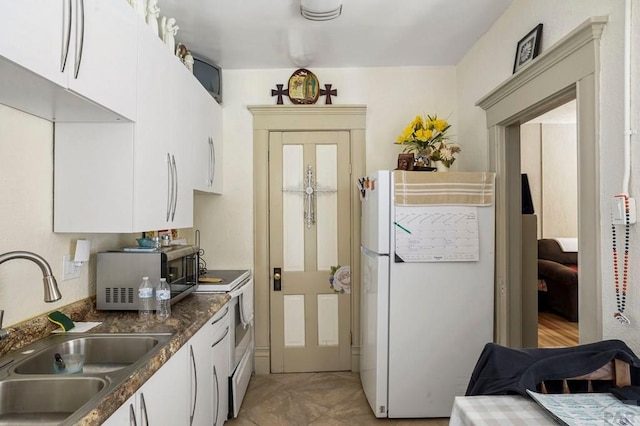 kitchen featuring freestanding refrigerator, stainless steel microwave, a sink, and white cabinetry