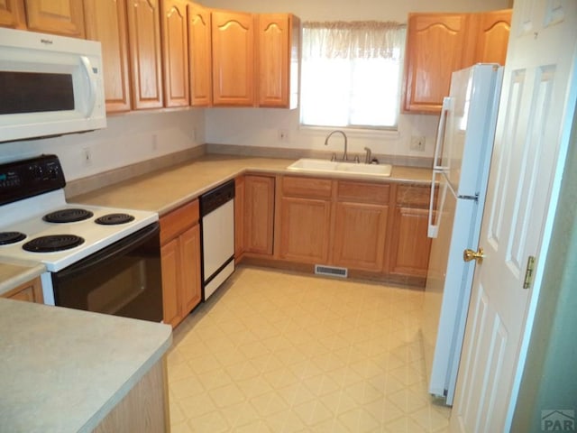 kitchen featuring white appliances, light countertops, and a sink