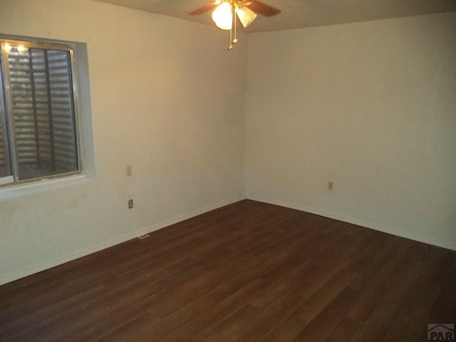 spare room featuring a ceiling fan, baseboards, and dark wood-type flooring