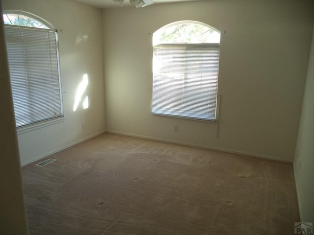 unfurnished room with baseboards, visible vents, and carpet flooring