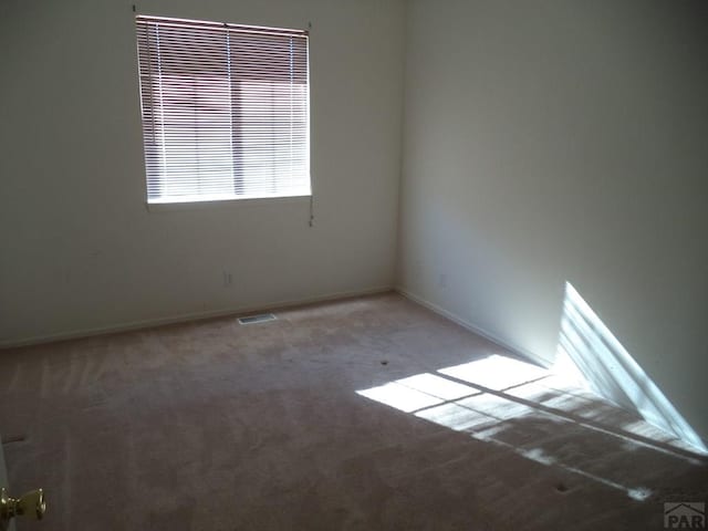 carpeted empty room featuring visible vents and baseboards