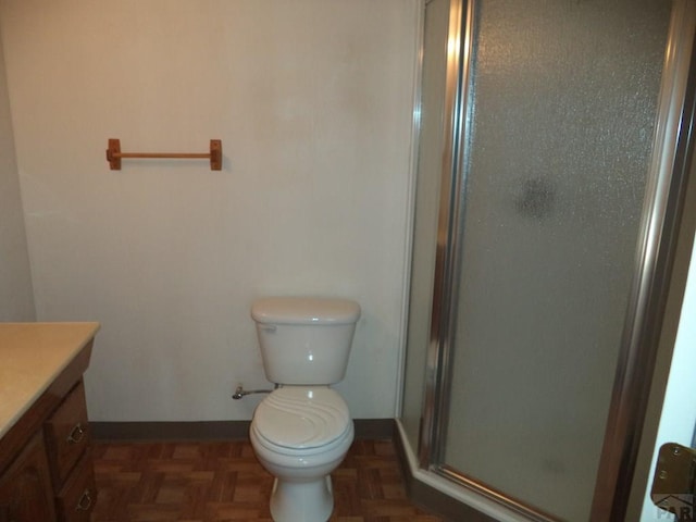 bathroom featuring a stall shower, baseboards, vanity, and toilet