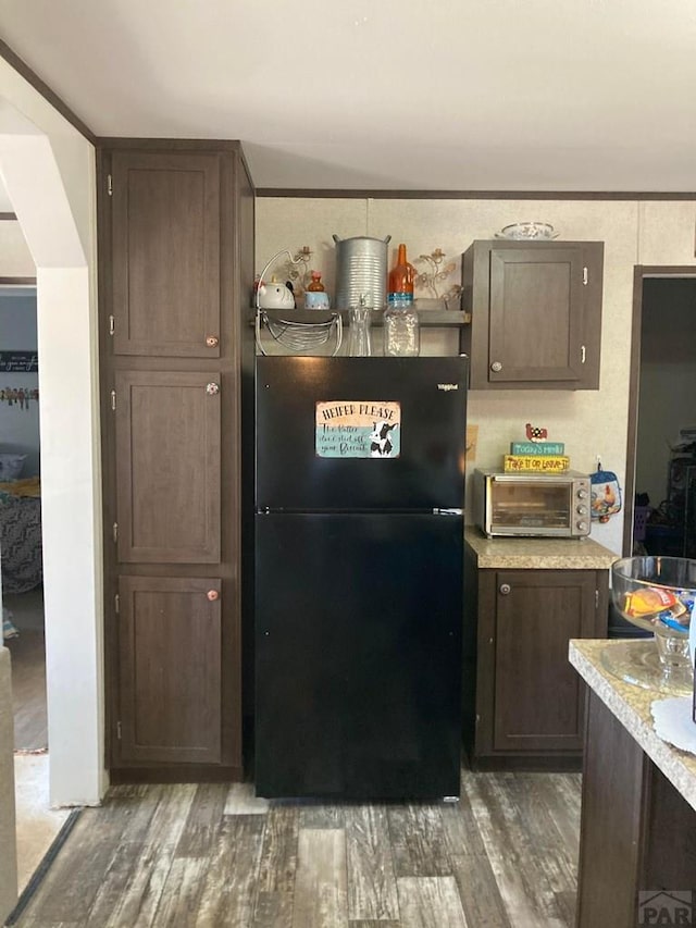 kitchen with freestanding refrigerator, a toaster, and dark brown cabinetry