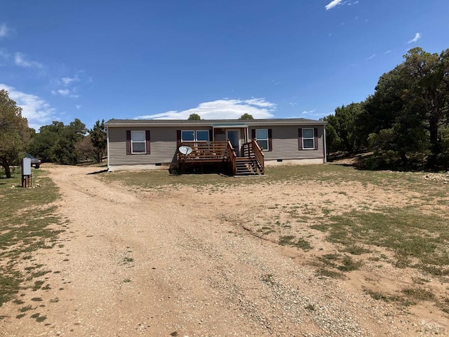 manufactured / mobile home featuring crawl space, a deck, and dirt driveway