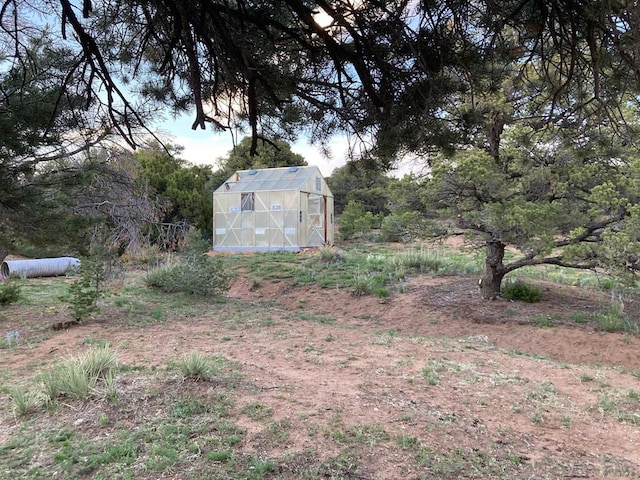 view of yard featuring a greenhouse and an outdoor structure