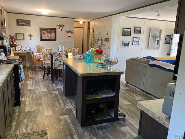 kitchen with arched walkways, under cabinet range hood, dark wood-type flooring, black stove, and a center island