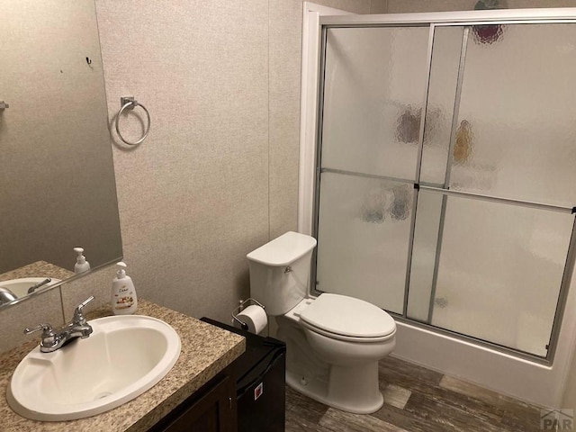 full bathroom with vanity, a shower stall, toilet, and wood finished floors