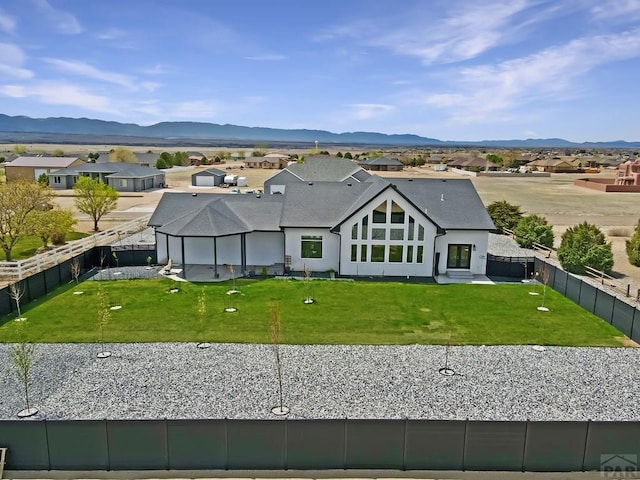 view of front of house with a fenced backyard, a front lawn, a mountain view, and a residential view