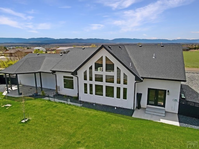 back of property featuring a yard, a patio area, stucco siding, and a mountain view