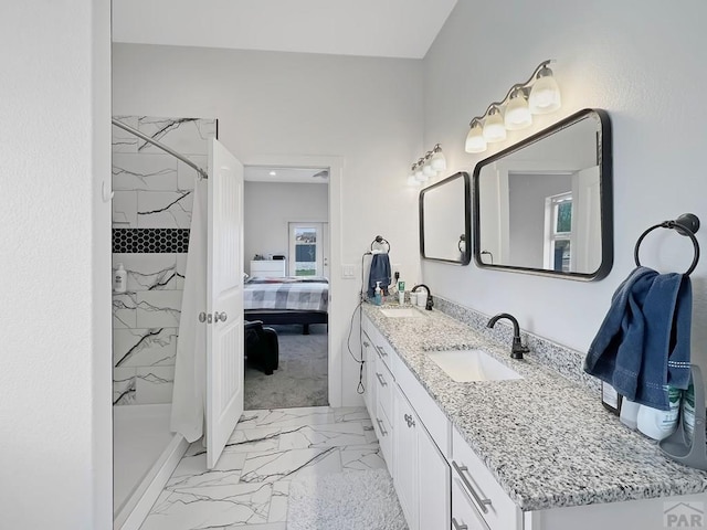 ensuite bathroom with double vanity, marble finish floor, a sink, and a marble finish shower