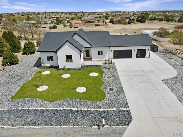 modern farmhouse featuring concrete driveway, fence, an attached garage, a front yard, and stucco siding