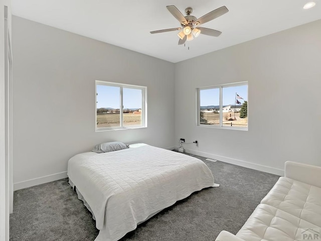 carpeted bedroom with ceiling fan, baseboards, and multiple windows