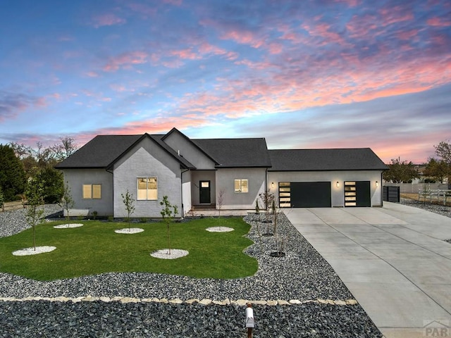 view of front of property with driveway, fence, a garage, a yard, and stucco siding