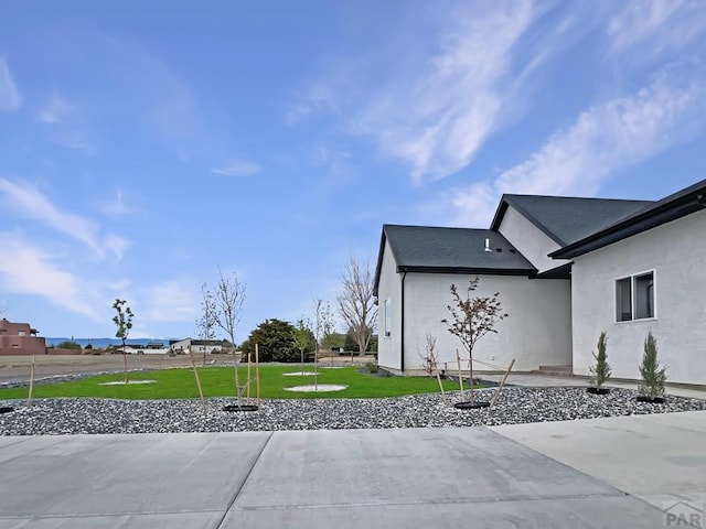 view of side of property with a lawn and stucco siding