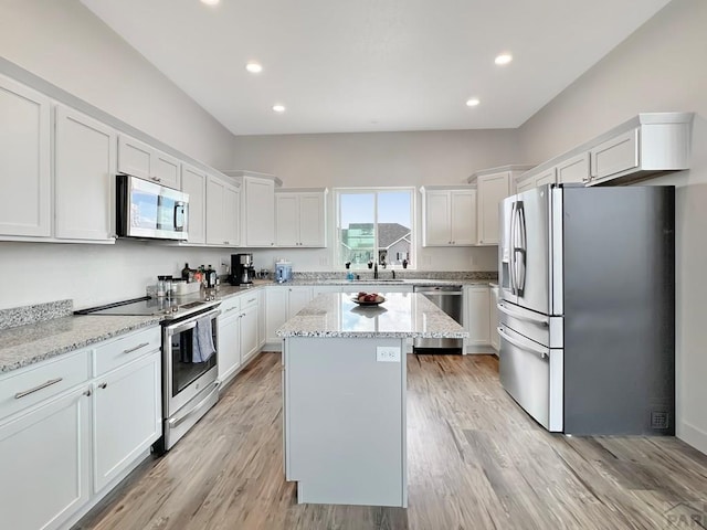 kitchen with white cabinets, recessed lighting, light stone countertops, a kitchen island, and appliances with stainless steel finishes